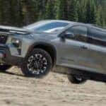 2024 Chevy Traverse driving on a sloped gravely trail by a forest