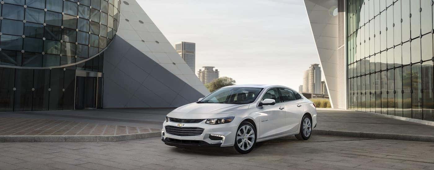 Showing off 2018 Chevy Malibu design with white paint in front of modern city buildings