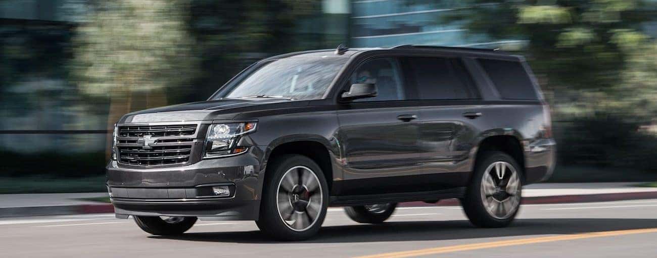 A dark grey 2019 Chevy Tahoe drives down a tree lined city street in Nashville