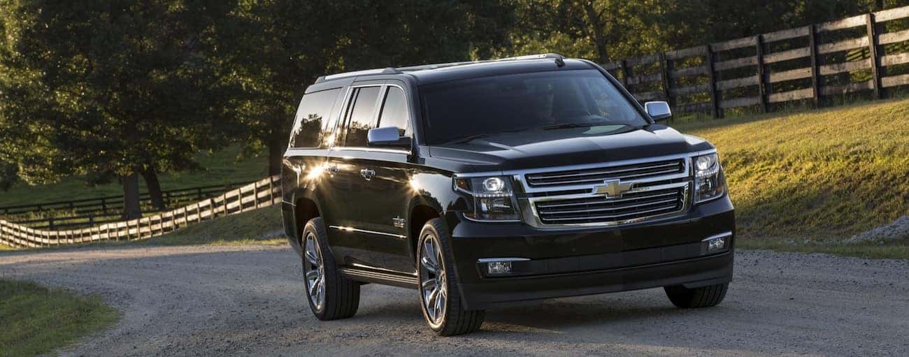 A sleek black 2019 Chevy Tahoe travels down a quite country road