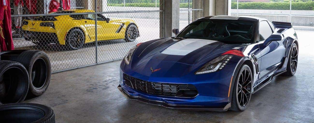 Blue 2019 Chevrolet Corvette Grand Sport in garage, yellow Corvette in back
