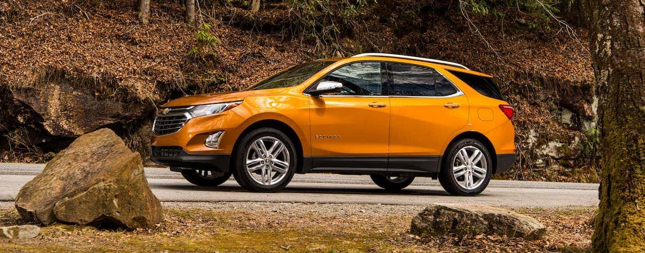 An orange 2019 Chevy Equinox drives up a leave-covered hill