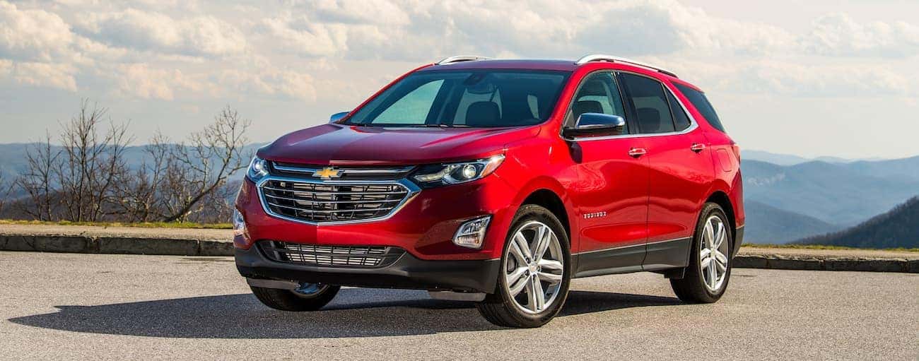 A red 2019 Chevy Equinox atop a hill with mountains a ways off in the background