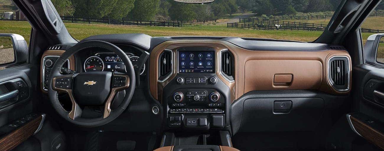 A brown and black leather interior of a 2019 Chevy Silverado overlooking a field with horses