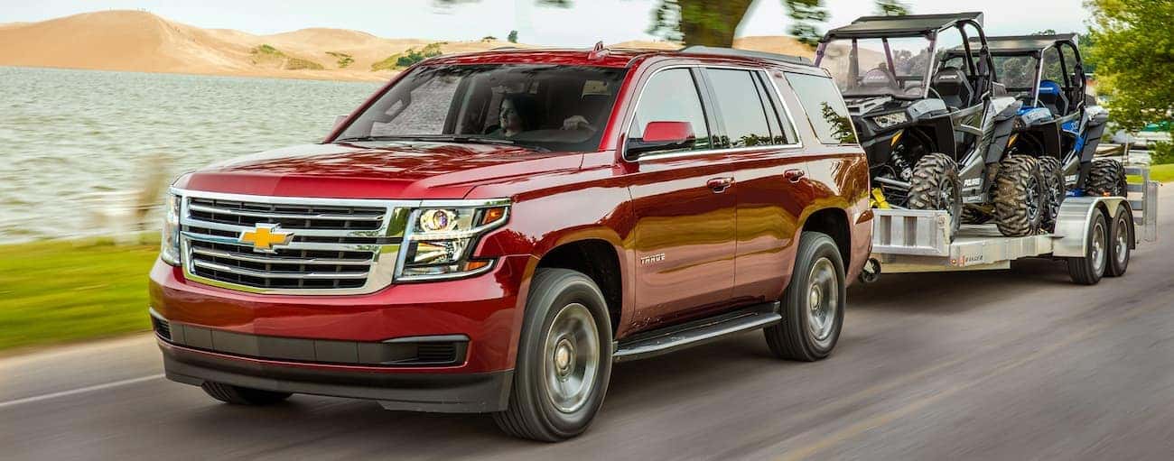 A red 2019 Chevy Tahoe towing a trailer with off road vehicles