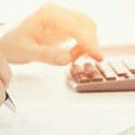 A person using a calculator and filling out a form