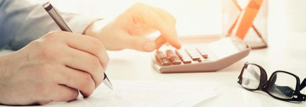 A person using a calculator and filling out a form
