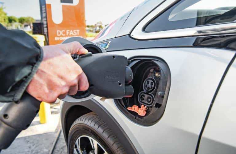 A person charging a 2020 Chevrolet Bolt EV at a DC fast charging station