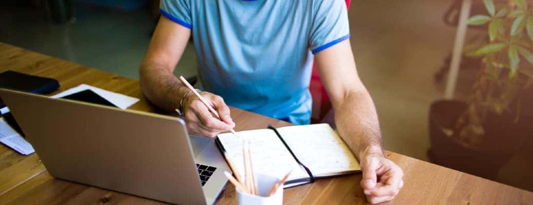a torso with a laptop and a notebook