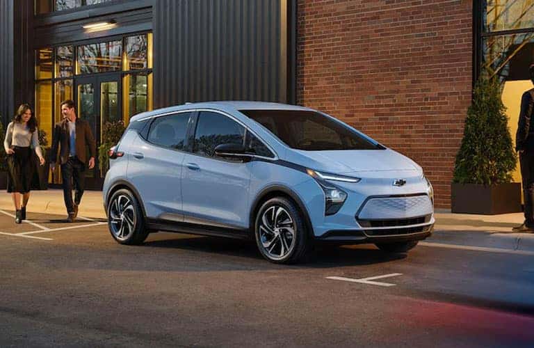 light blue 2022 Chevrolet Bolt EV by a building