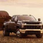 A 2022 Chevy Silverado 3500 towing a huge payload of hay, as seen in the middle of a hayfield