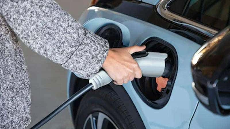 A woman charging a 2022 Chevy Bolt EV, helping to illustrate What Is the Range of the 2022 Chevy Bolt EV? 