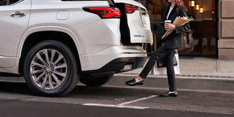 A woman accessing the cargo storage area of a Chevy Traverse by using the motion sensor opener.