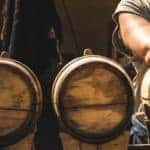 A man standing behind some whiskey barrels as a means of illustrating Fun Things to Do in Nashville 2023.