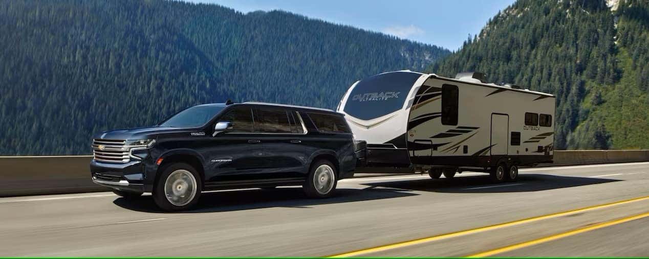The 2023 Chevy Suburban, which has excellent powertrain options, towing a large camper trailer.
