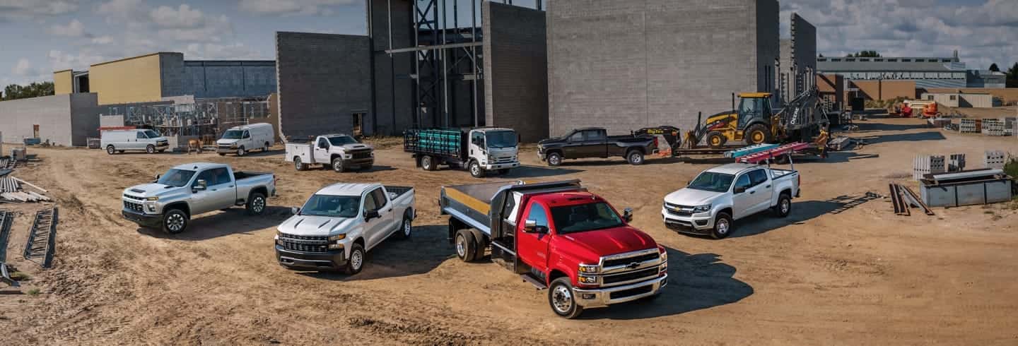 A couple of Chevrolet trucks parked in a construction field.