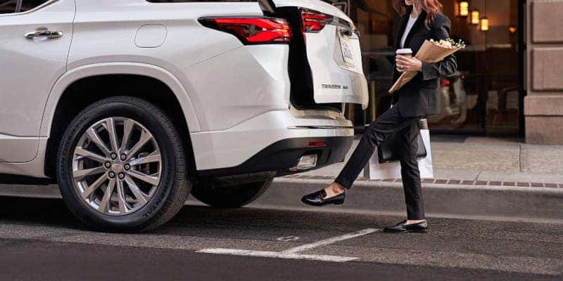 A woman operating the hands-free tailgate in the 2023 Chevy Traverse, which is an excellent family SUV.