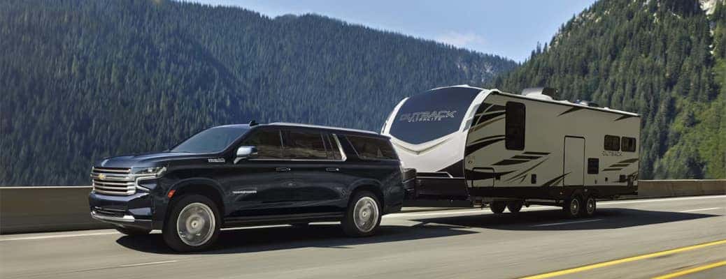 The 2024 Chevy Suburban towing a large camper trailer.