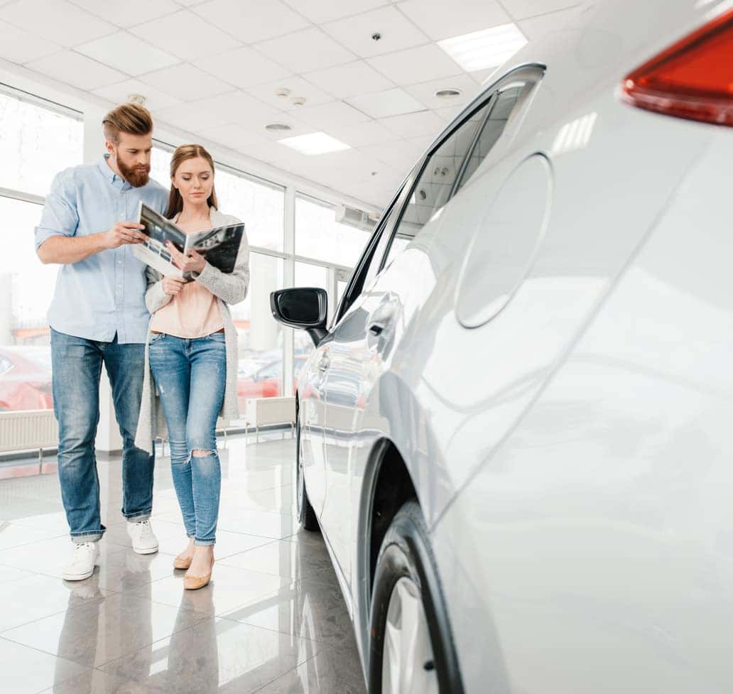 Couple reviewing vehicle options while walking through a Chevrolet dealership showroom near Hendersonville, Tennessee.