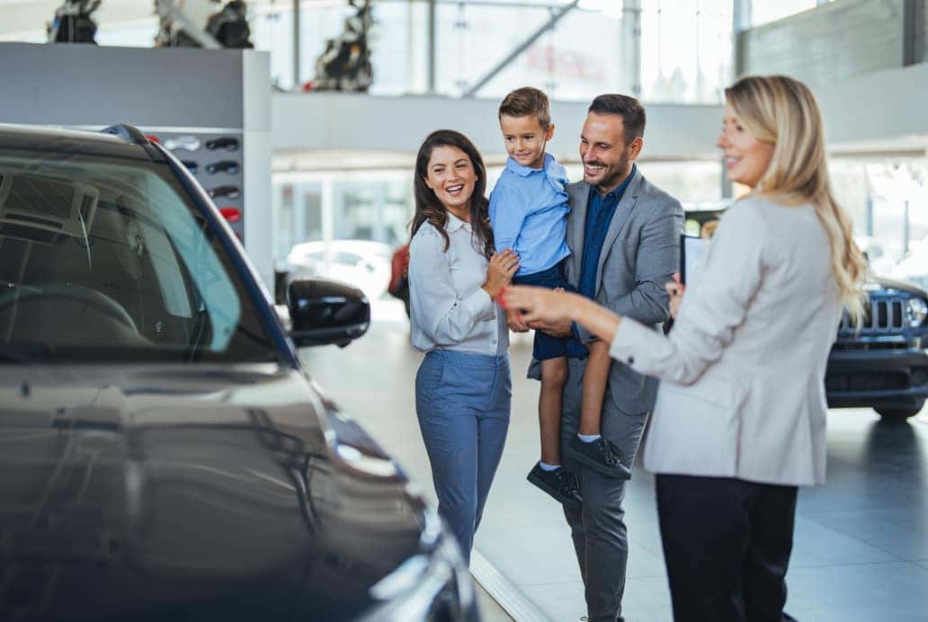 Family exploring vehicle options with a dealership representative in a Chevrolet showroom near Hendersonville, Tennessee.
