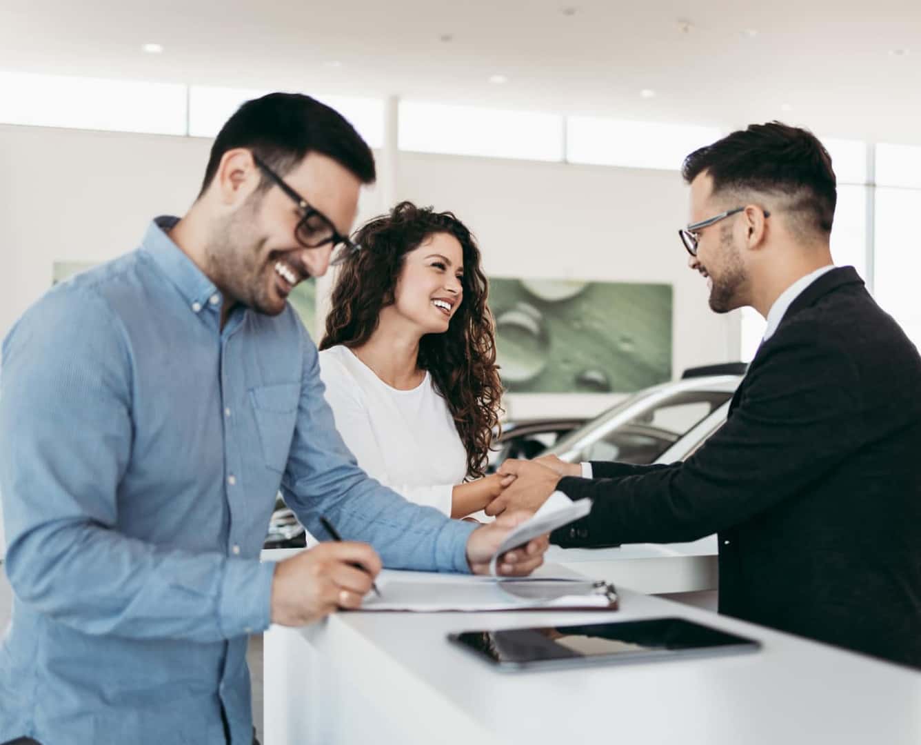 Customers completing paperwork and discussing vehicle financing options with a dealership representative.