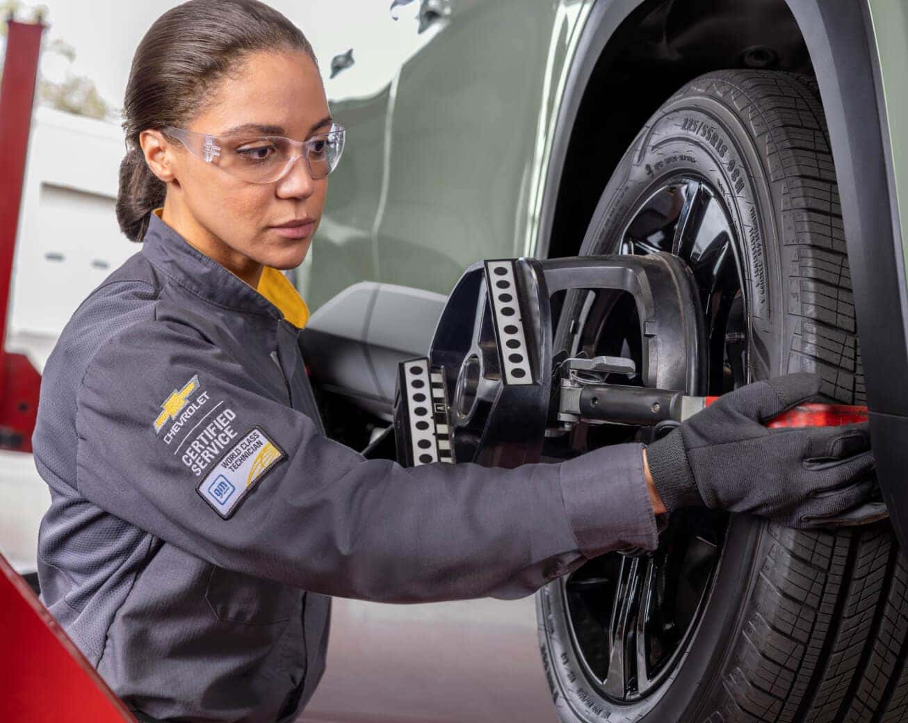 Chevrolet Certified Service technician performs a wheel alignment on a vehicle using specialized equipment.
