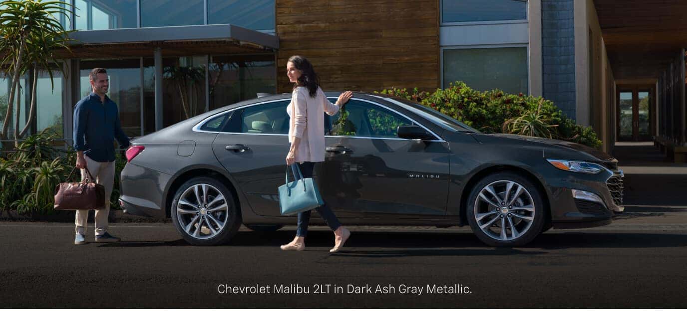 Profile of a Chevrolet Malibu 2LT in Dark Ash Gray parked in a modern home driveway.