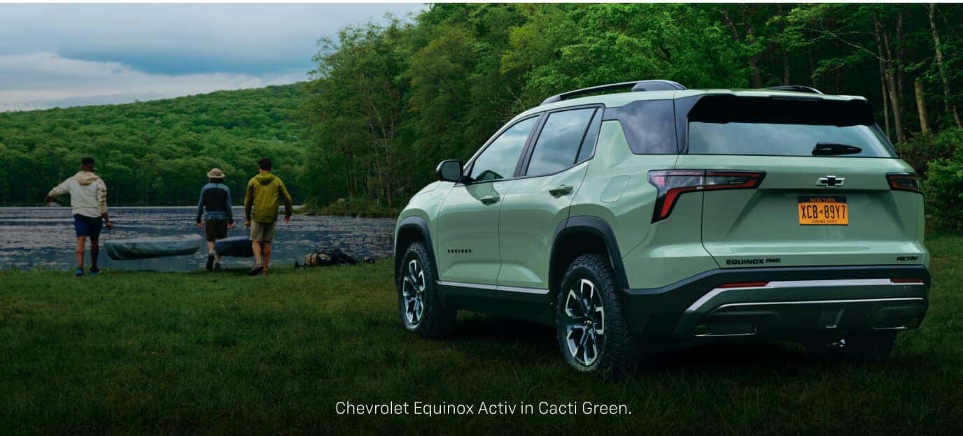 Three-quarter rear view of a Chevrolet Equinox ACTIV in Cacti Green parked near people by a lake.