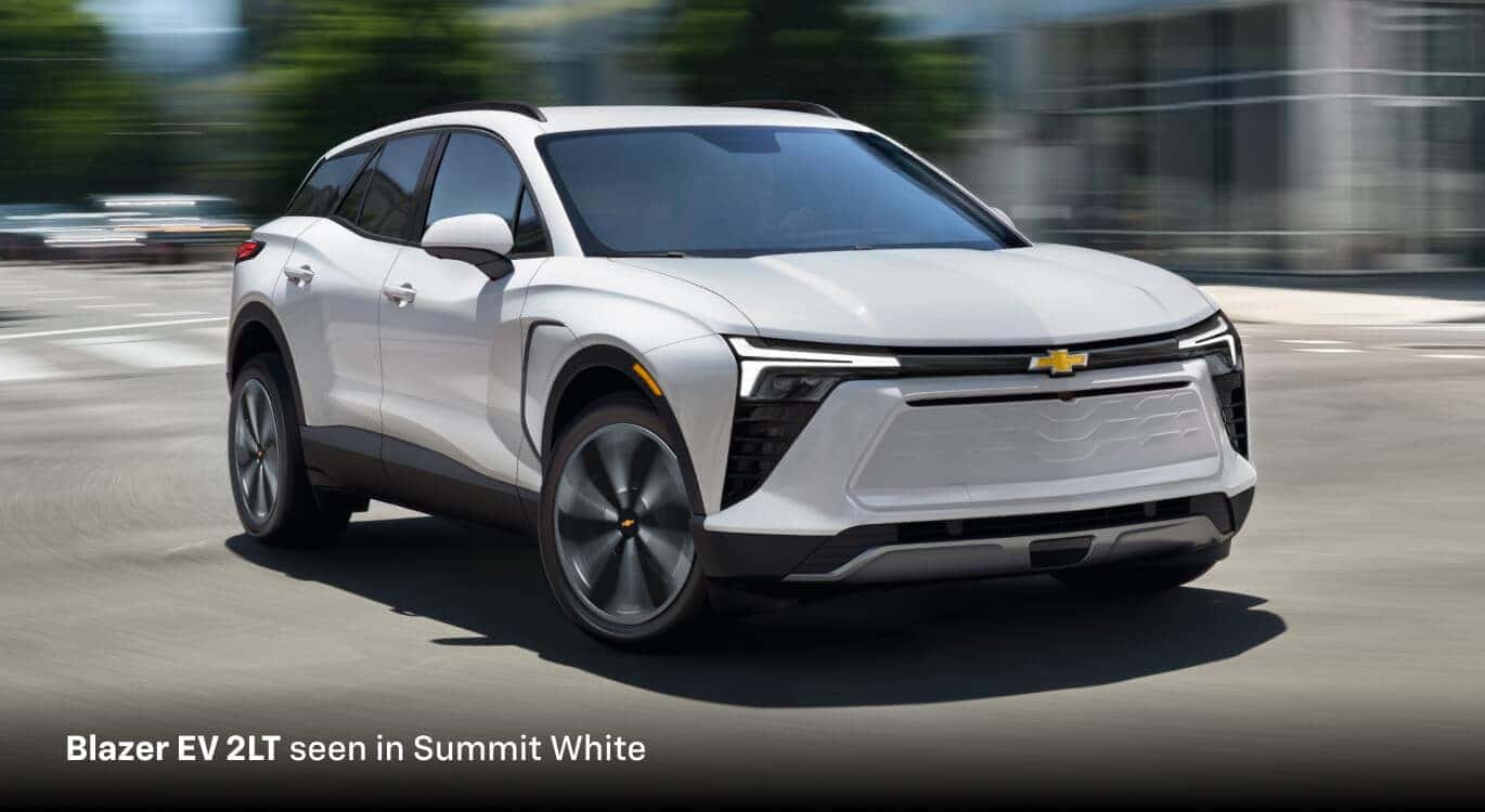 2027 Chevrolet Blazer EV 2LT in Summit White, front three-quarter passenger-side view driving on a city street.