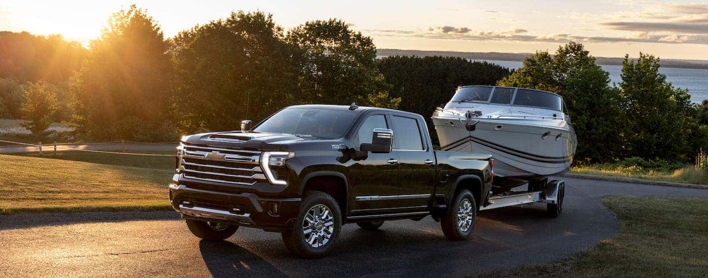 A black 2025 Chevy Silverado 2500 HD High Country is shown from the front at an angle after leaving a Chevy dealer near Coventry.