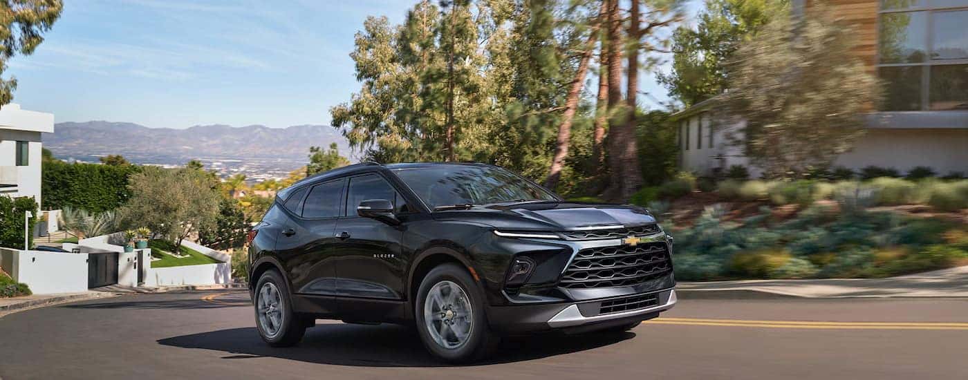 A black 2025 Chevy Blazer driving through a neighborhood.