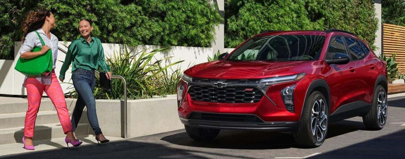 A red 2025 Chevy Trax RS is shown parked near a Chevy dealer in Vernon.