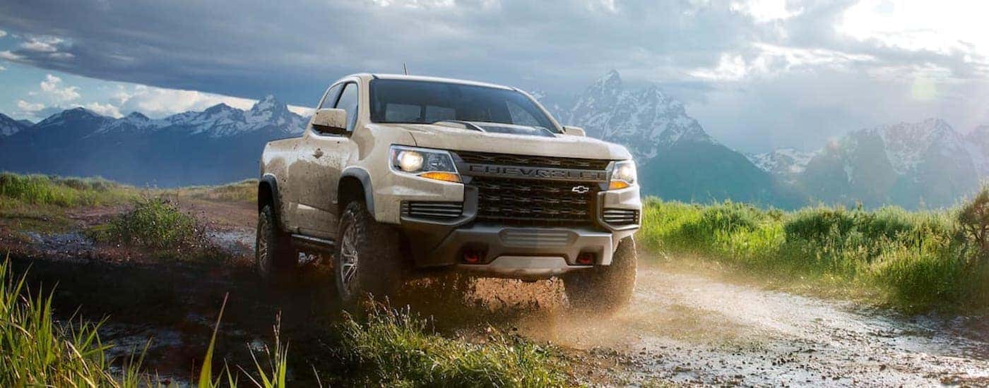 A tan 2021 Chevy Colorado ZR2 driving down a muddy road.