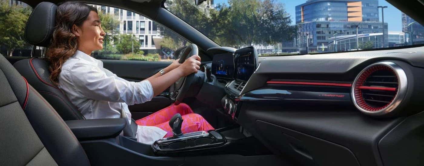 A woman driving a 2024 Chevy Trax RS in a city