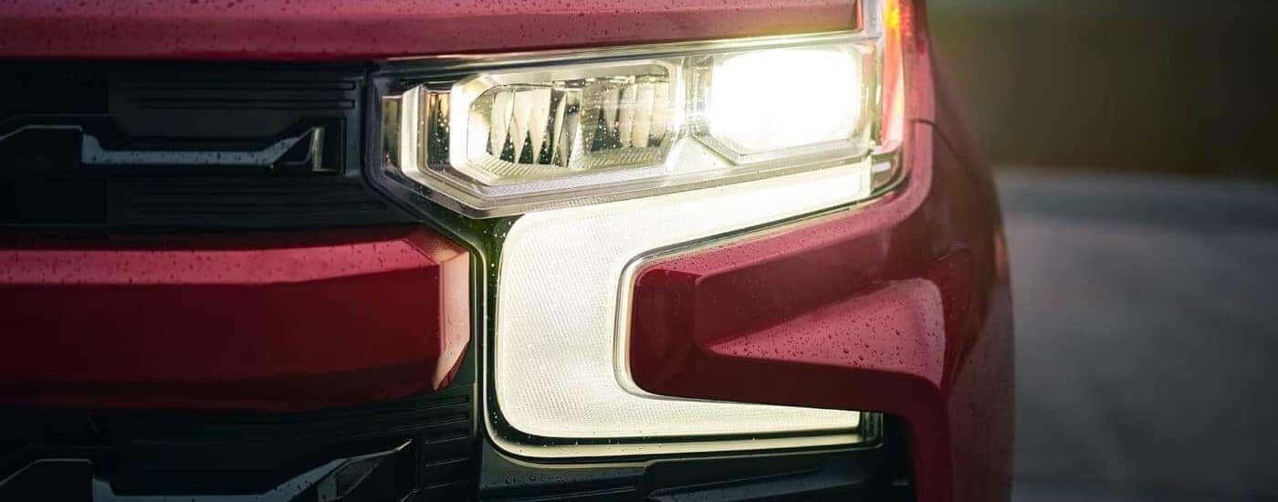 Close-up on the headlights of a red 2025 Chevy Silverado 1500.