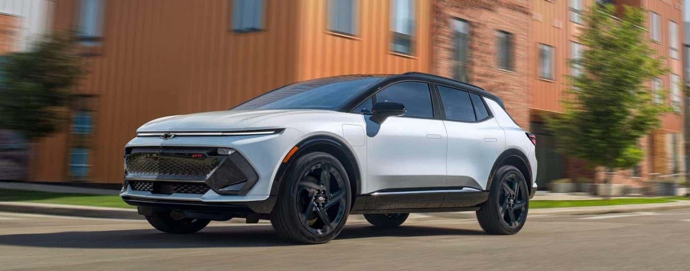 A white 2025 Chevy Equinox EV RS driving in a city.