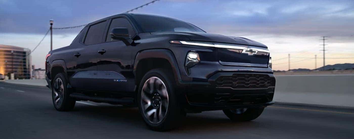 A black 2025 Chevy Silverado EV driving to view a Chevy EV for sale near Manchester.