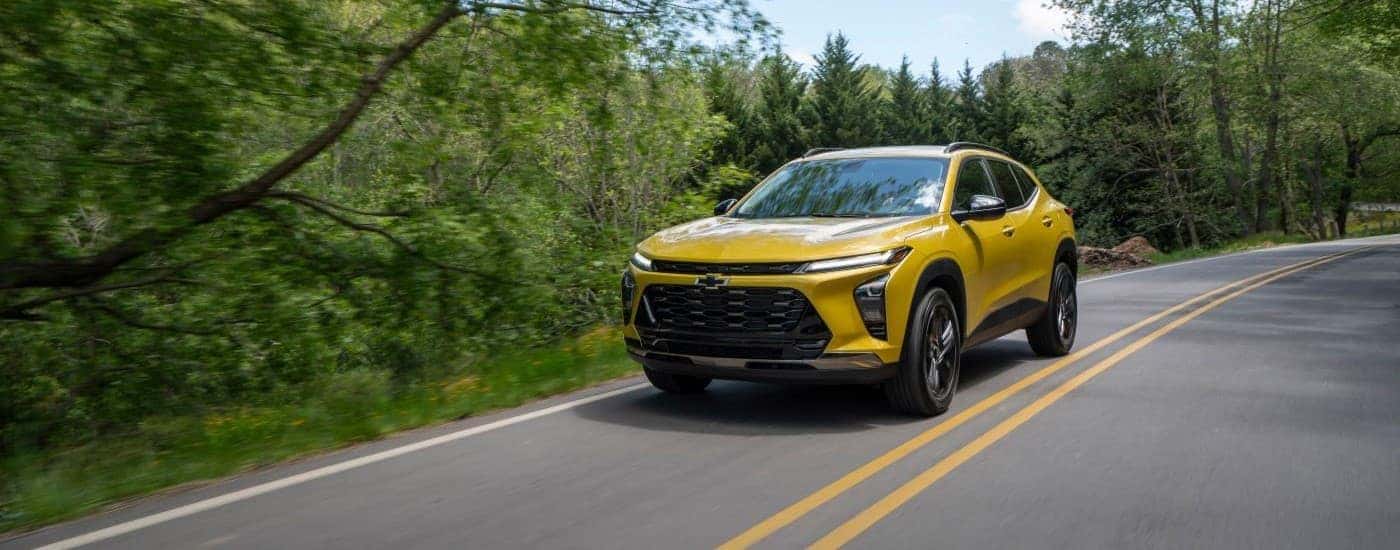 A yellow 2025 Chevy Trax ACTIV driving on a highway.