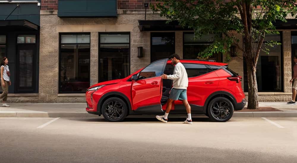 Person opening the door of a red 2027 Chevy Bolt RS