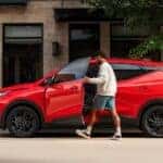 A red 2027 Chevy Bolt parked in a city.