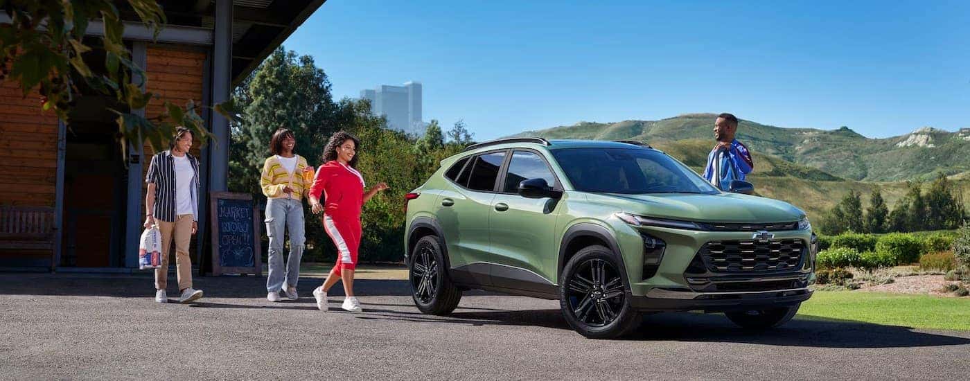 A green 2026 Chevy Trax ACTIV parked near several people on a sunny day.