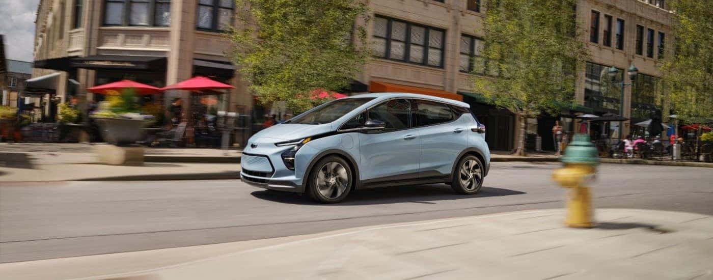 A silver 2023 Chevy Bolt driving in a city