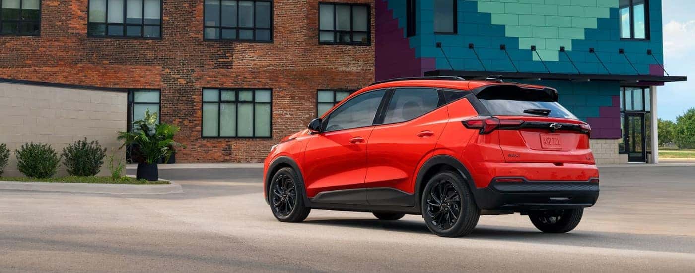 Red 2027 Chevy Bolt RS from the rear in front of a brick building