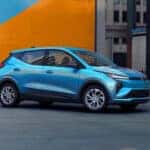 A blue 2027 Chevy Bolt parked in a city