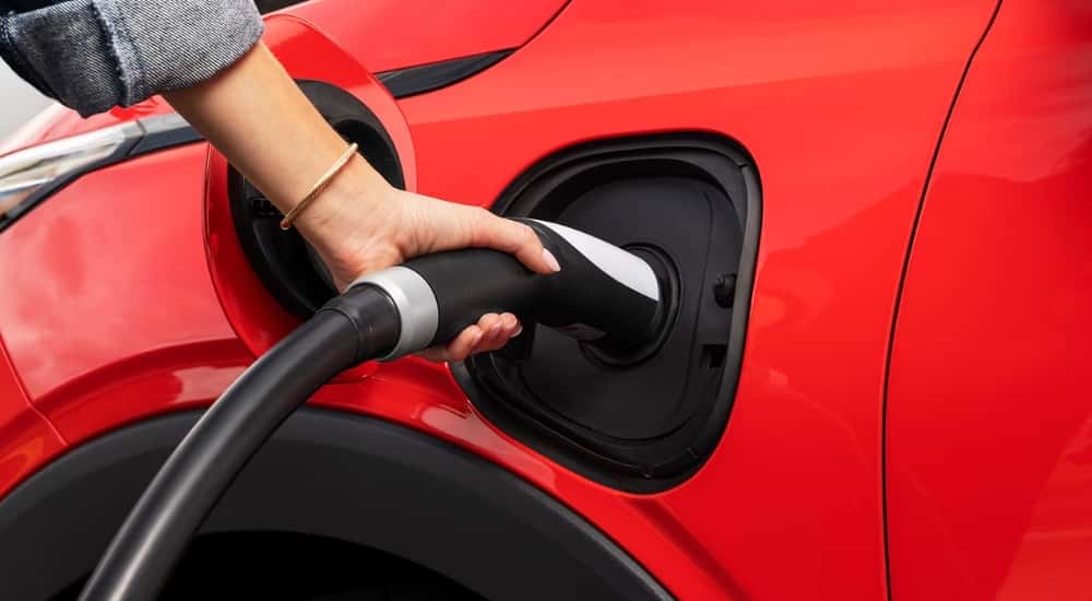 A charger plugged into a red 2027 Chevy Bolt RS