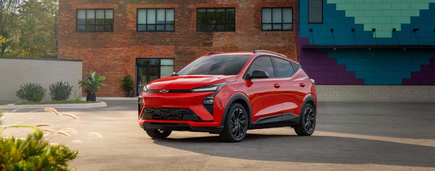 Red 2027 Chevy Bolt RS parked in front of a brick building