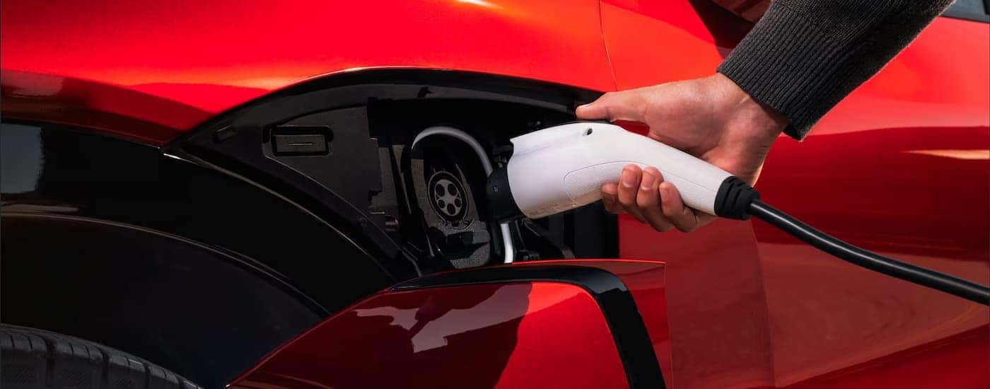 A red 2026 Chevy Blazer EV being plugged in