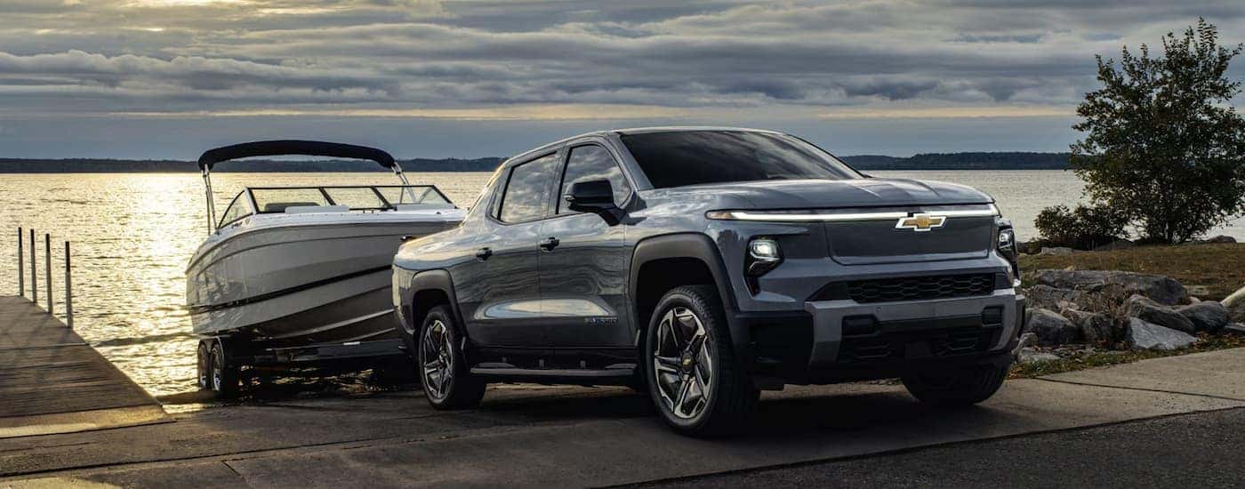 A black 2026 Chevy Silverado EV towing a boat