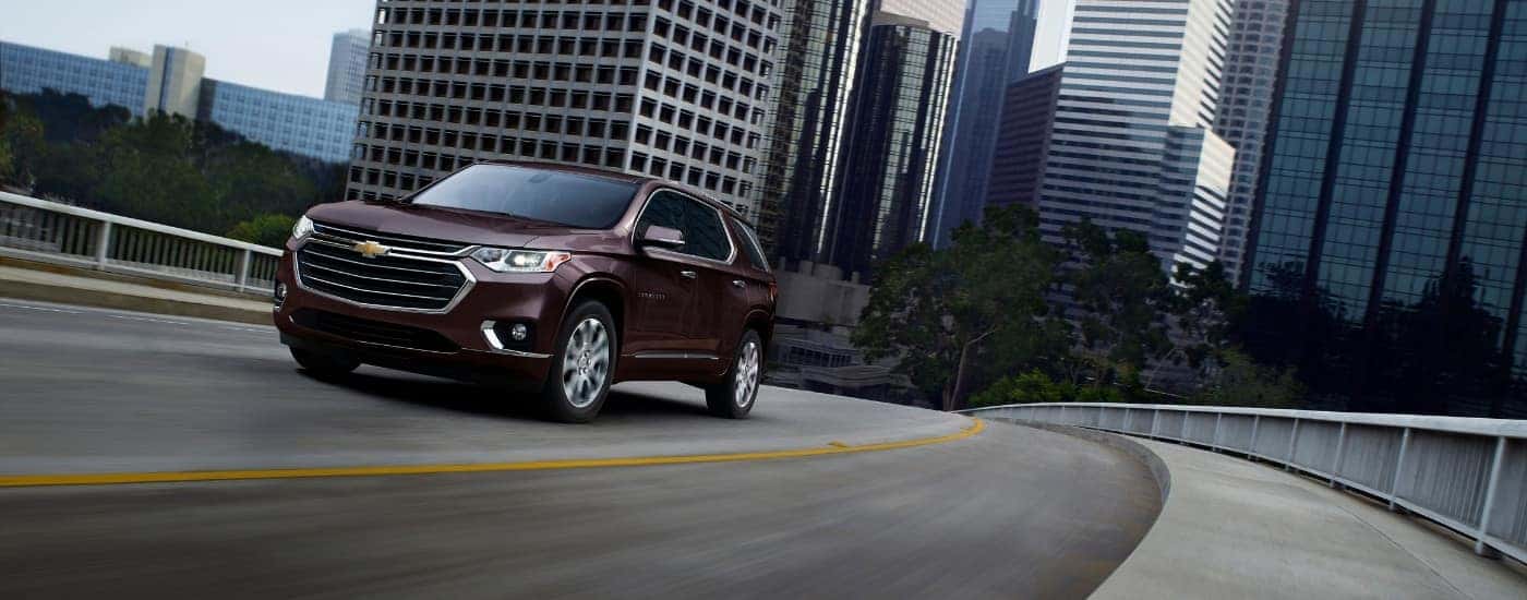 A maroon 2019 Chevy Traverse driving away from city.