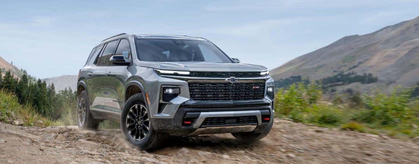 A gray 2026 Chevy Traverse driving on a rocky mountain trail.